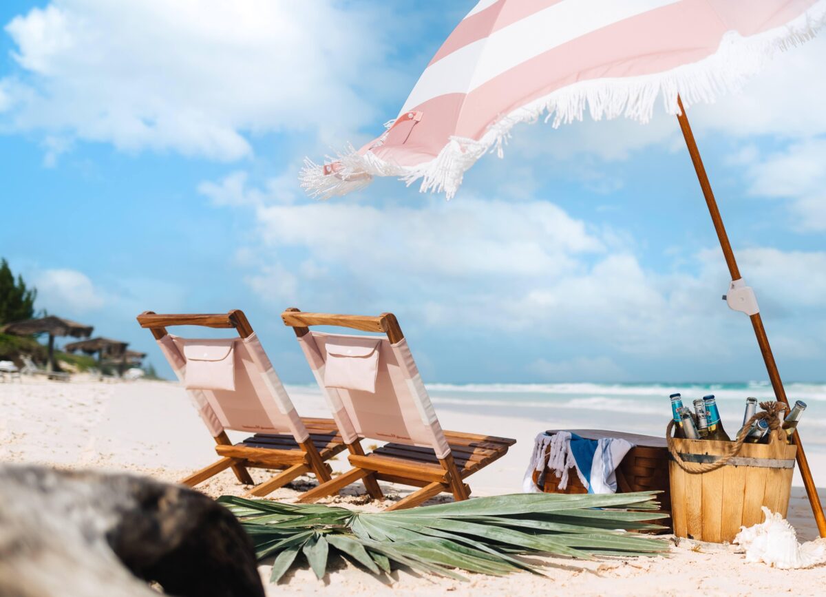 Beach chairs and umbrella set up on sandy shore.